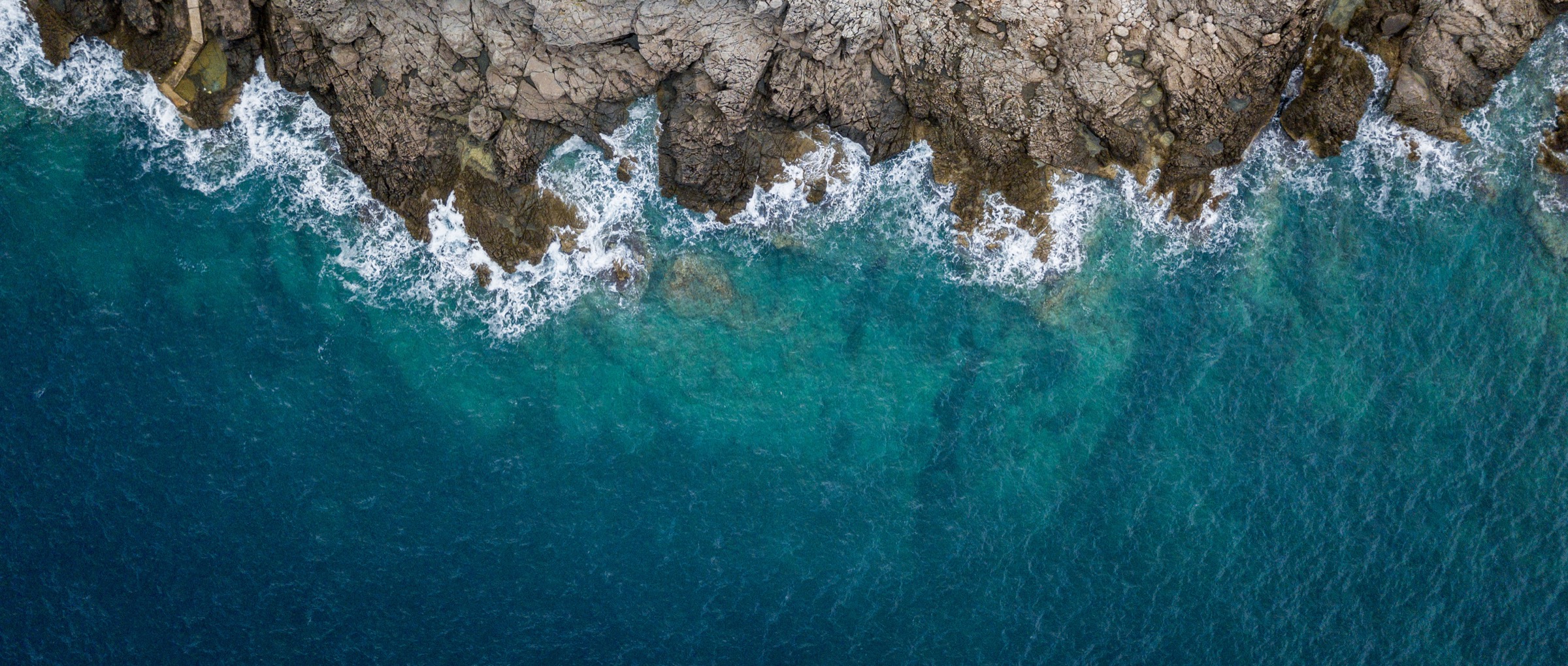 Aerial view of waves meeting a rocky shoreline