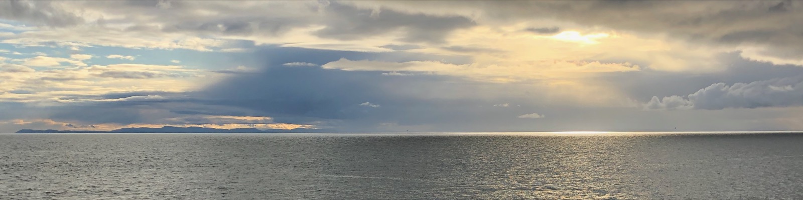Light breaking through clouds over a distant shoreline