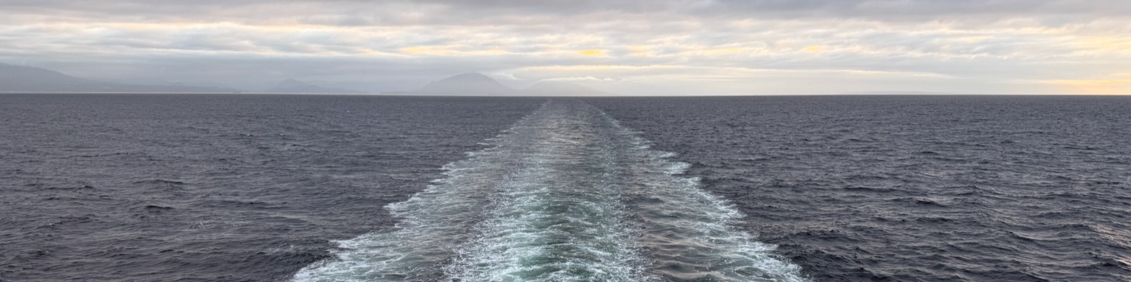A wake opening a path across the water toward a distant coast