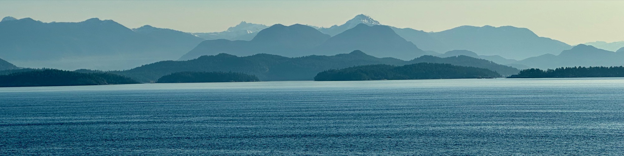 Layered coastal mountains and forested islands across blue water